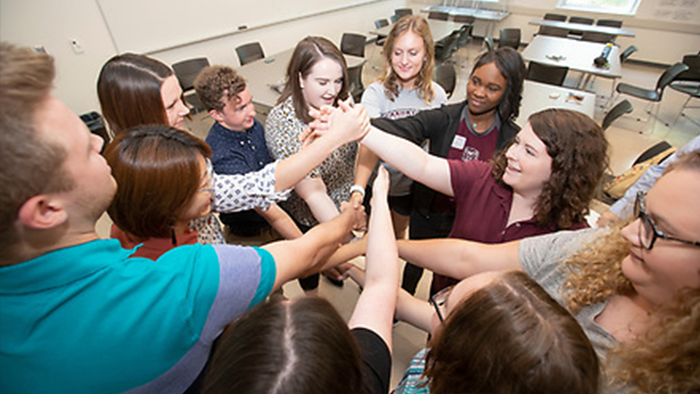 A group of students putting their hands together in a huddle.