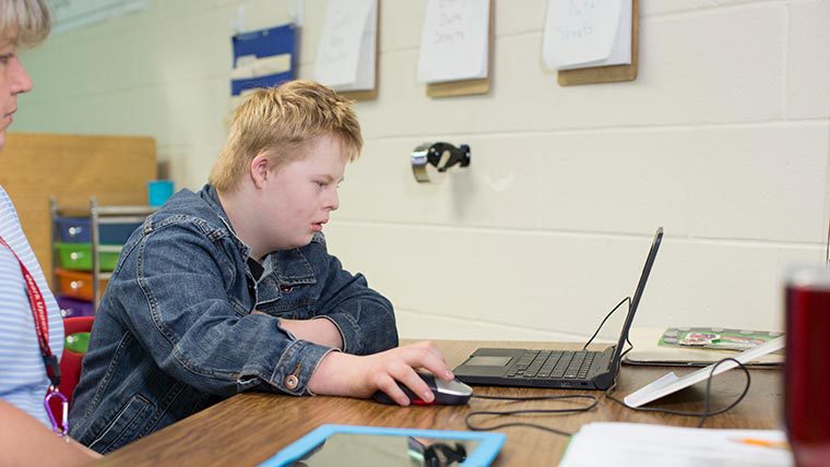 Special education student doing class work on laptop.