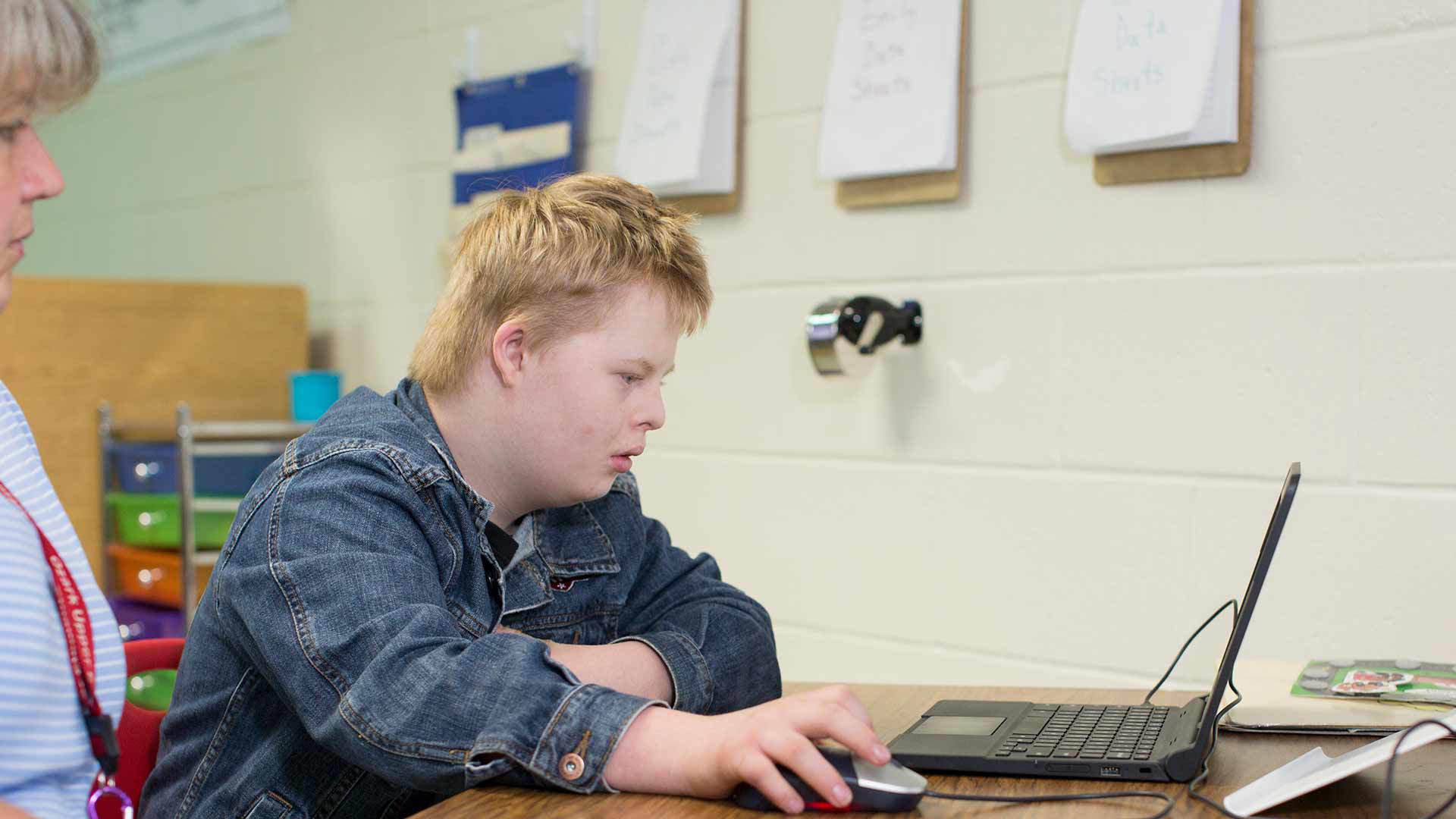 Special education student doing class work on laptop.
