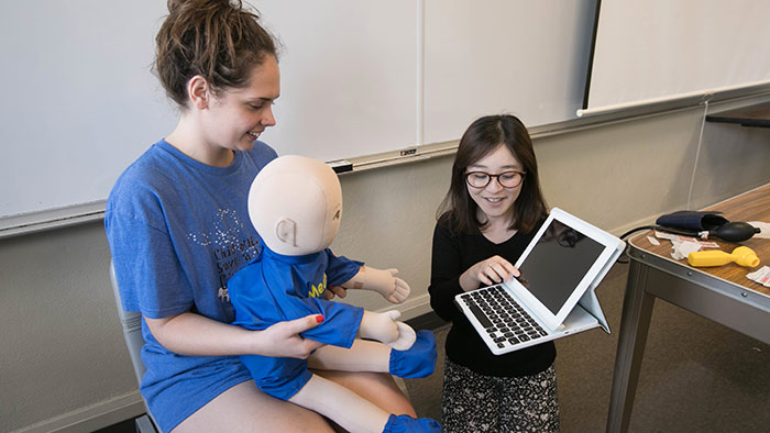 Students using doll to simulate scenarios with hospitalized child