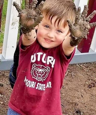 Young boy with muddy hands in the air