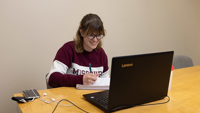 A student in a Missouri State sweatshirt studies on her laptop in Meyer Library.