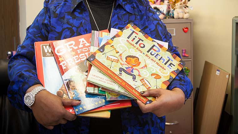 Teacher holding a stack of children's books.