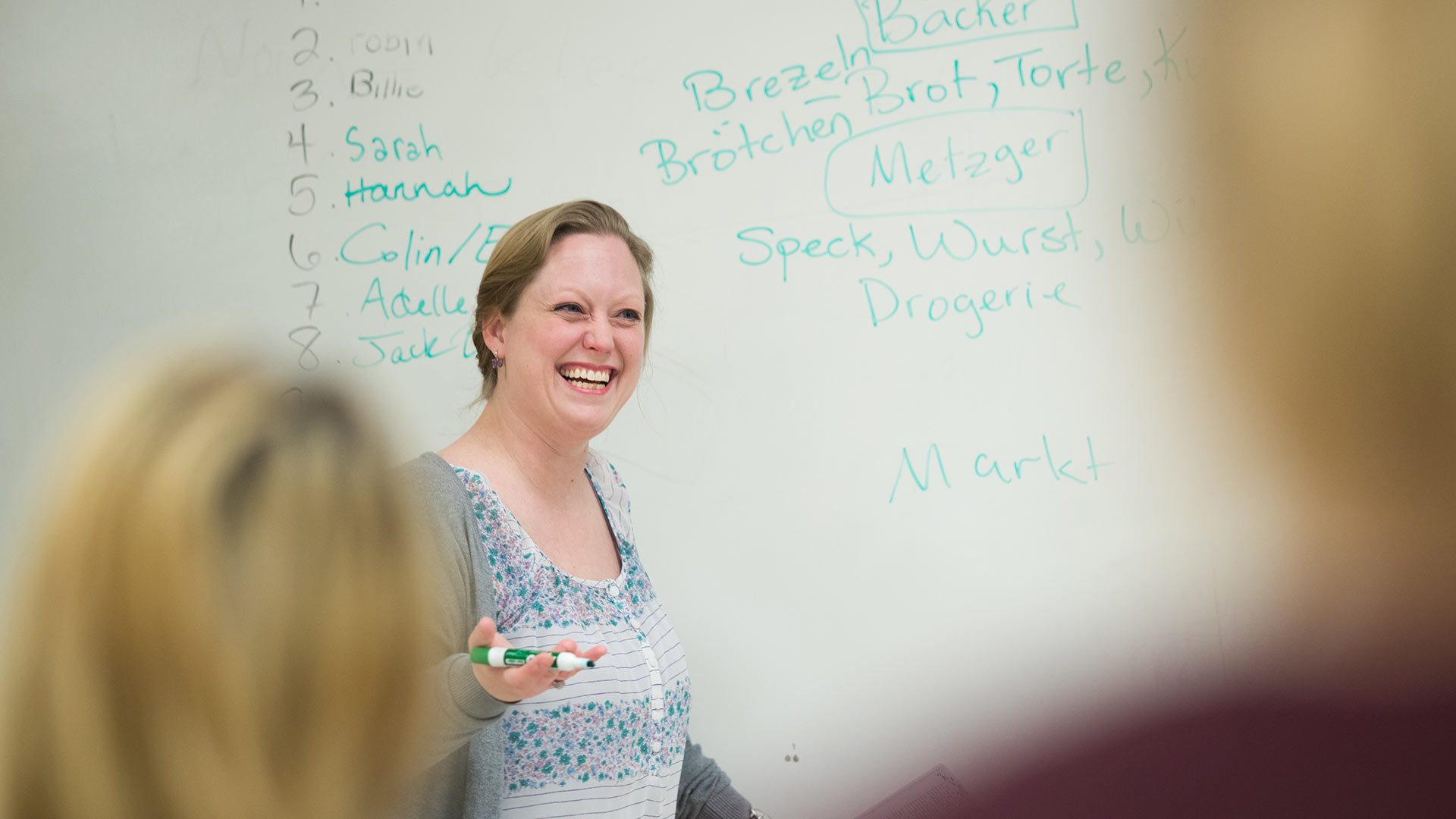 A language teacher smiles while teaching class.