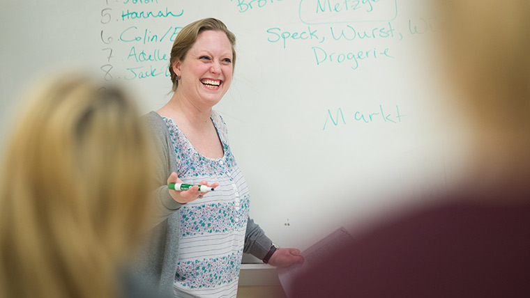 A language teacher smiles while teaching class.