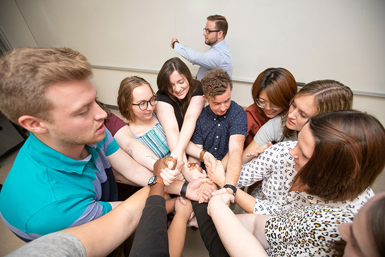 Students in a circle clasping hands.