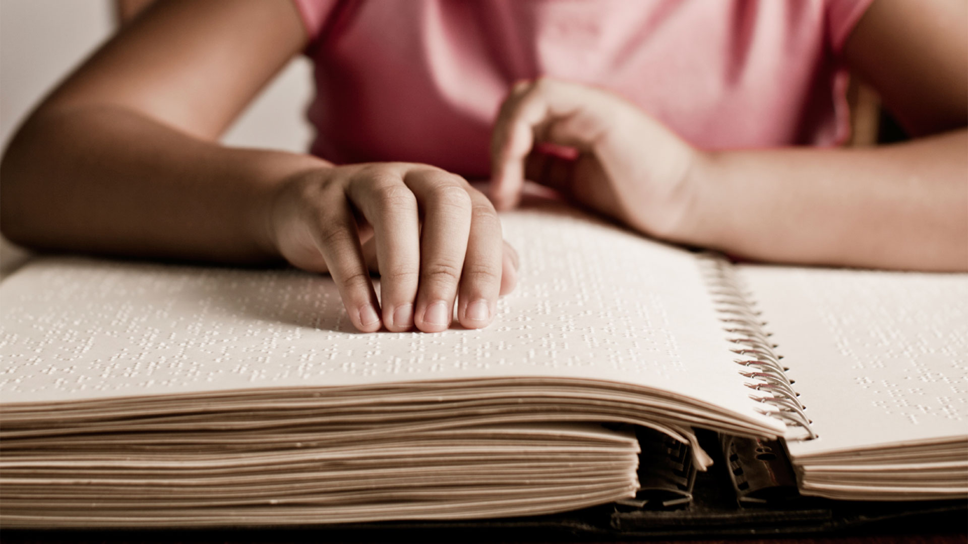 A child reading a Braille book