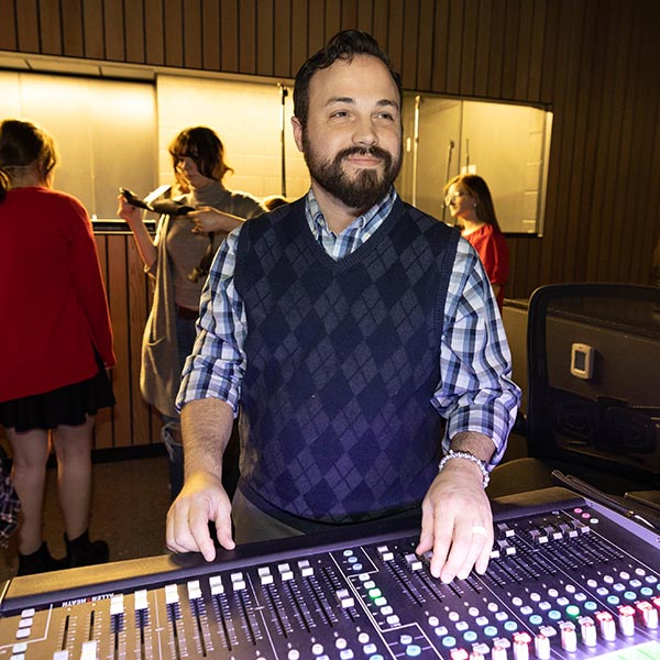 Cory Glenn standing behind a soundboard during theater class at Nixa High School.