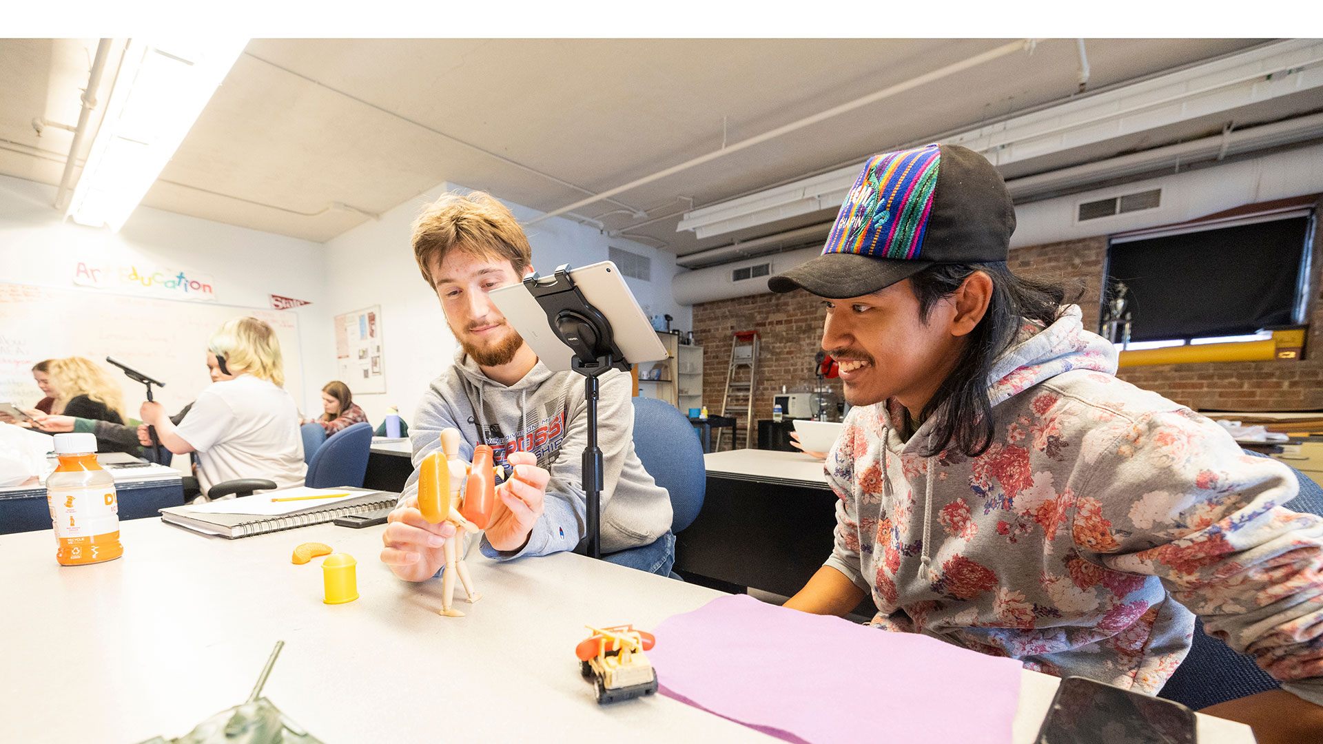Two students position a mannequin doll for a project in an art education class.