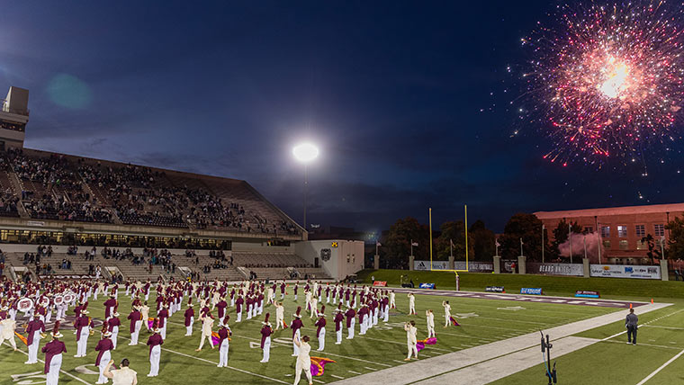 Missouri State Pride Band performing at halftime of a football game with fireworks in the sky.