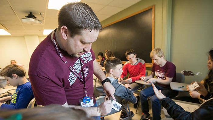 Student teacher giving lesson in middle school classroom. 