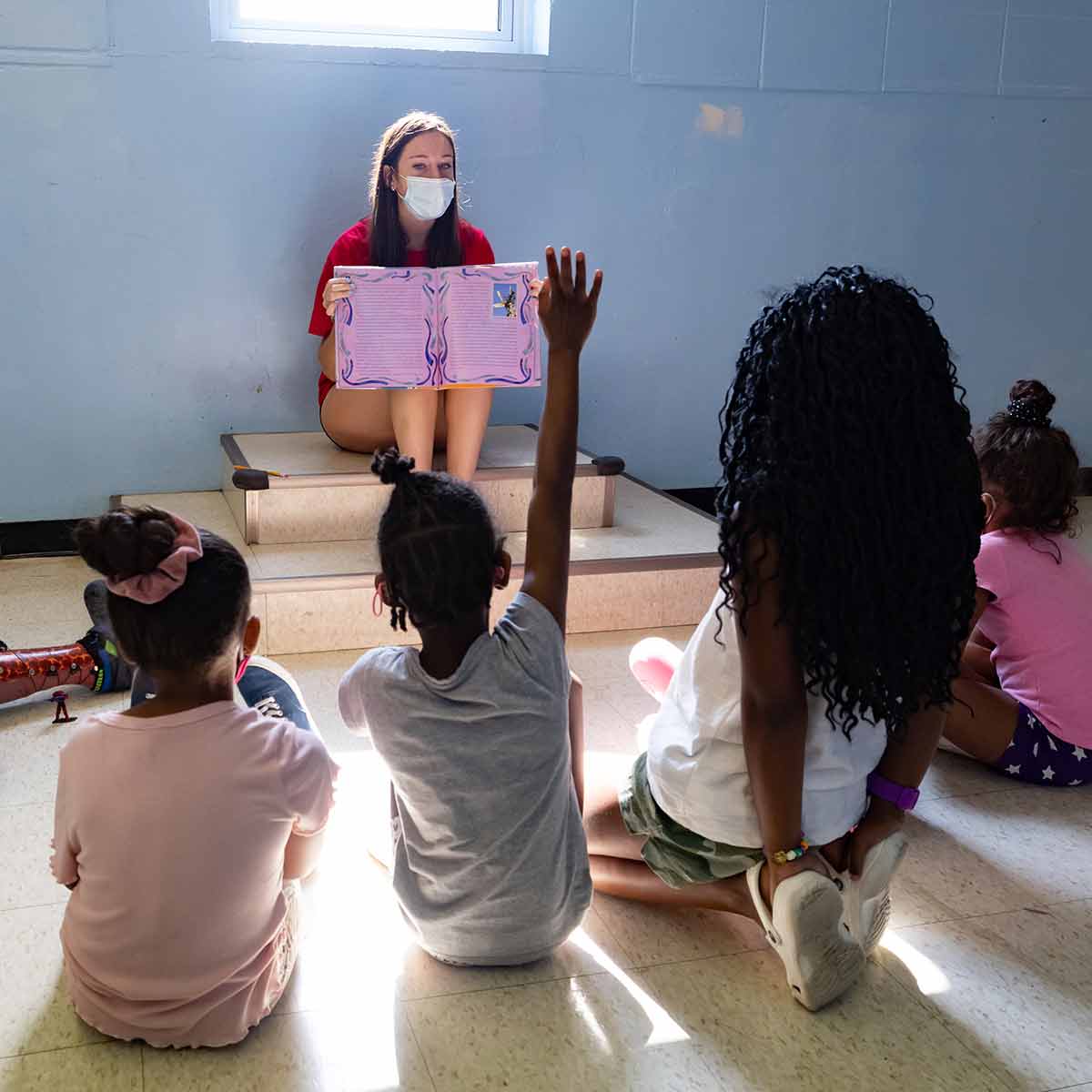 A teacher reading a book to a small group of students.