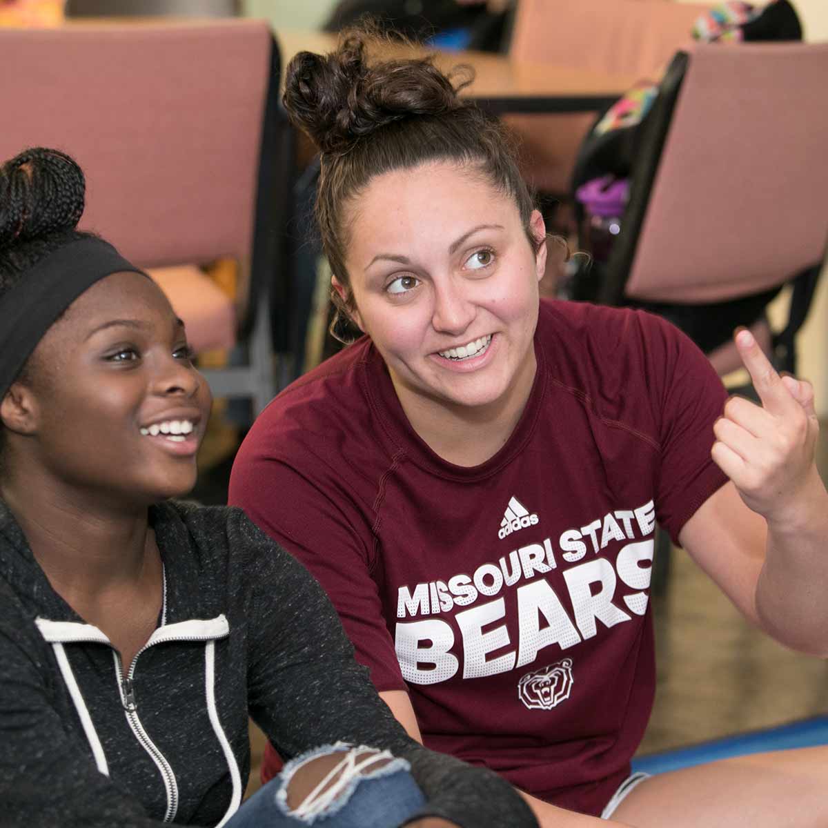 A student-teacher from Missouri State and a middle school student share a laugh.