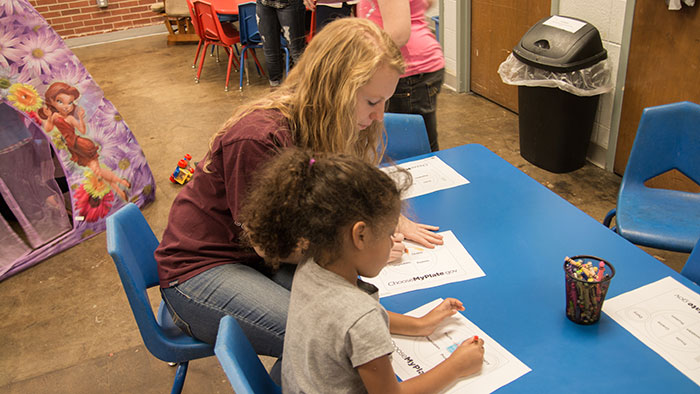 Missouri State student doing coloring sheet with child. 