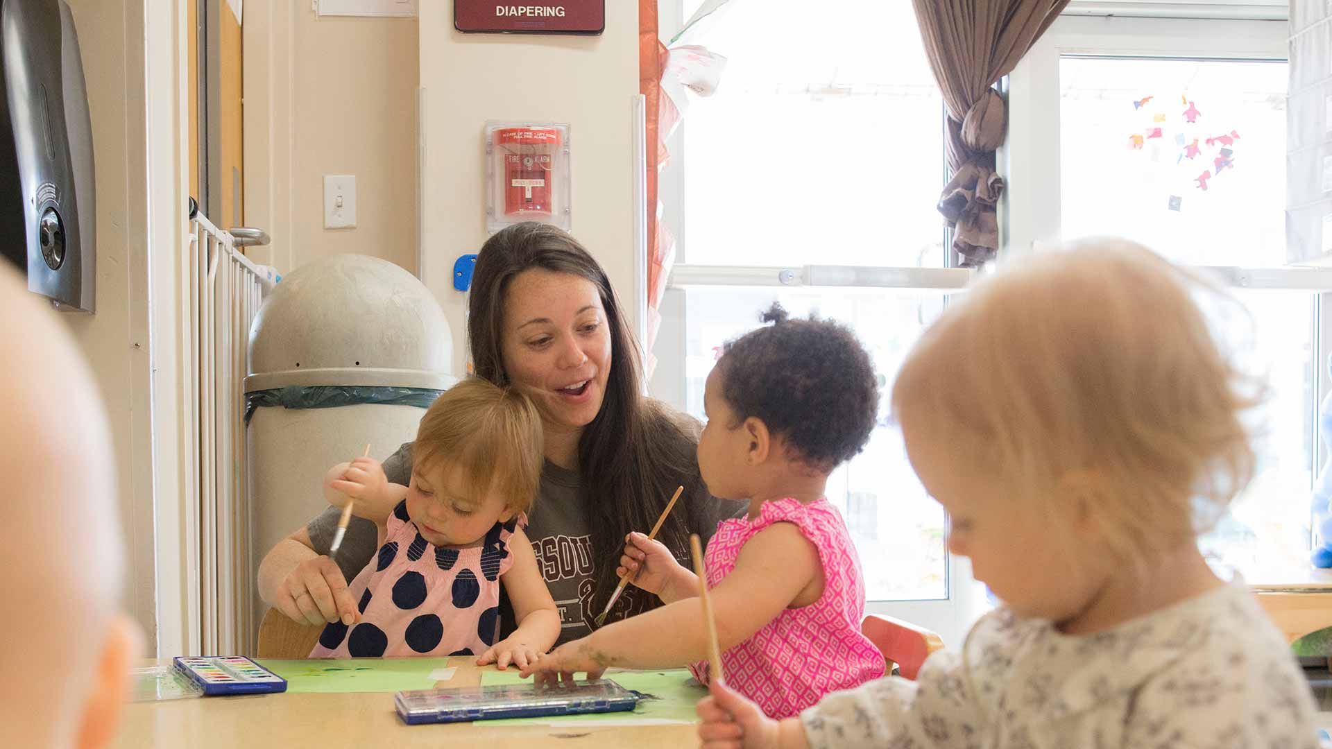 Student helping three toddlers.