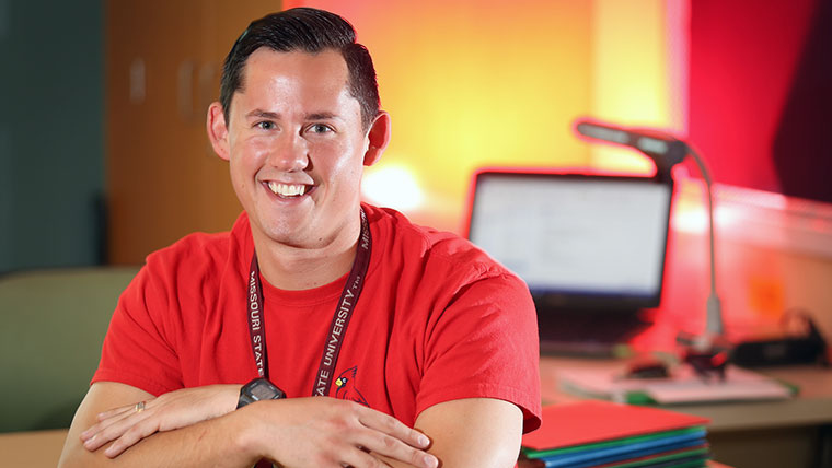 Smiling business teacher standing with crossed arms