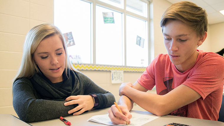 A teacher at a student's desk.