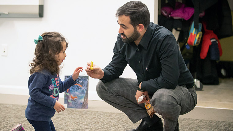 Teacher within a classroom offering a student a puzzle piece.