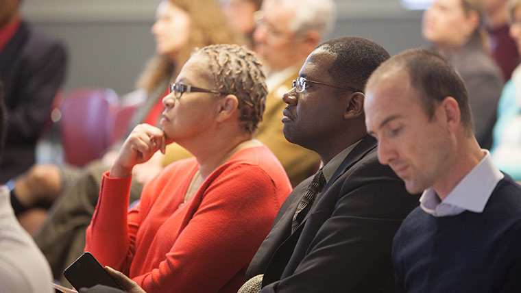 Three people listening attentively to a speaker discuss diversity initiatives.