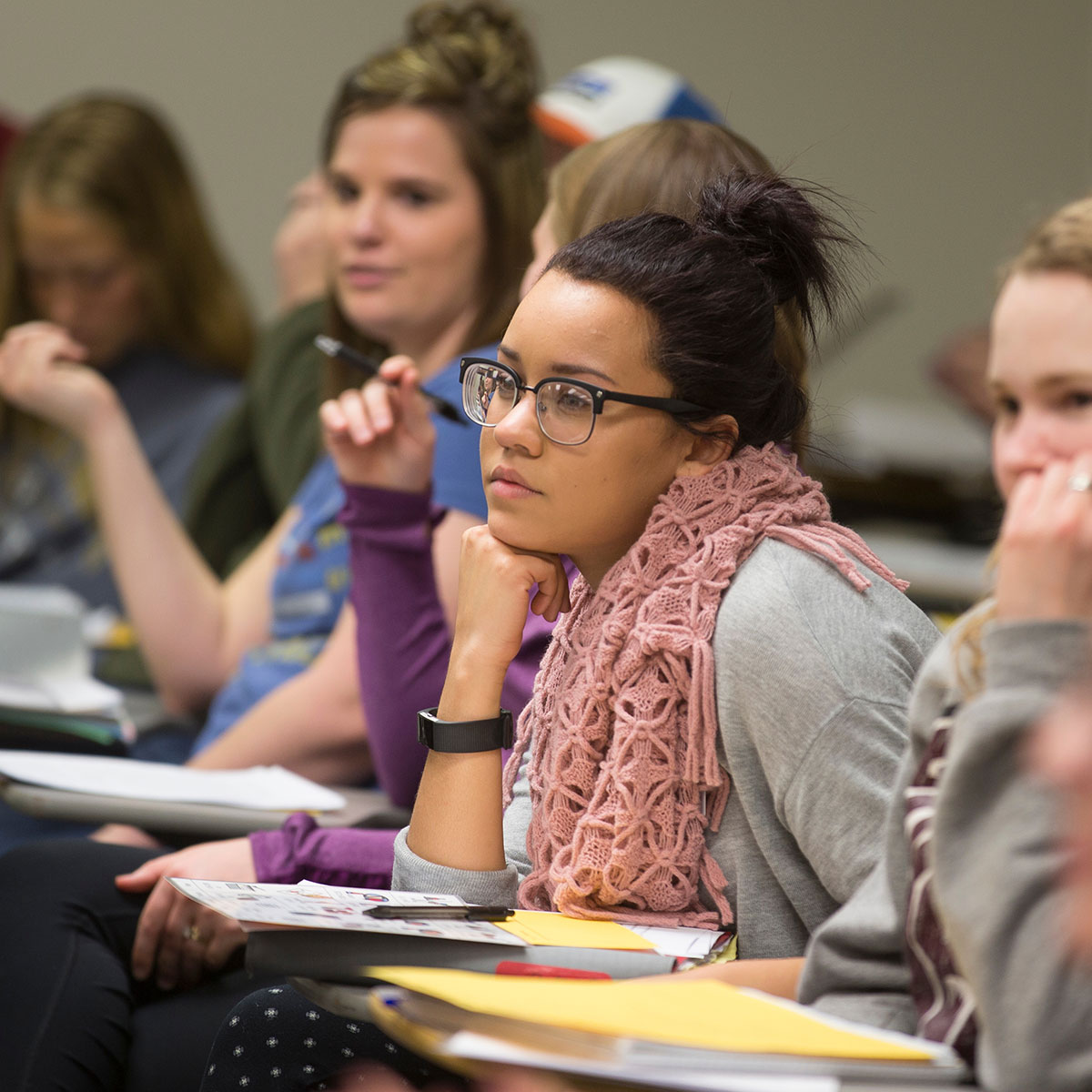 A student is seated at a desk and focuses on the instructor.