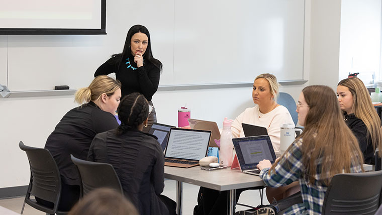 Dr. Kayla Lewis, professor of reading, foundations and technology, listens to her student in her Foundations of Literacy and Instruction class.