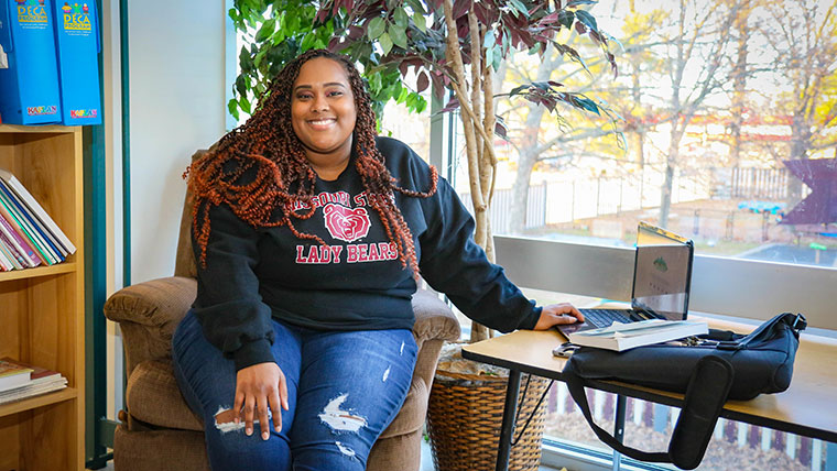 Grad student Aaliyah Williams is seated in a school library.