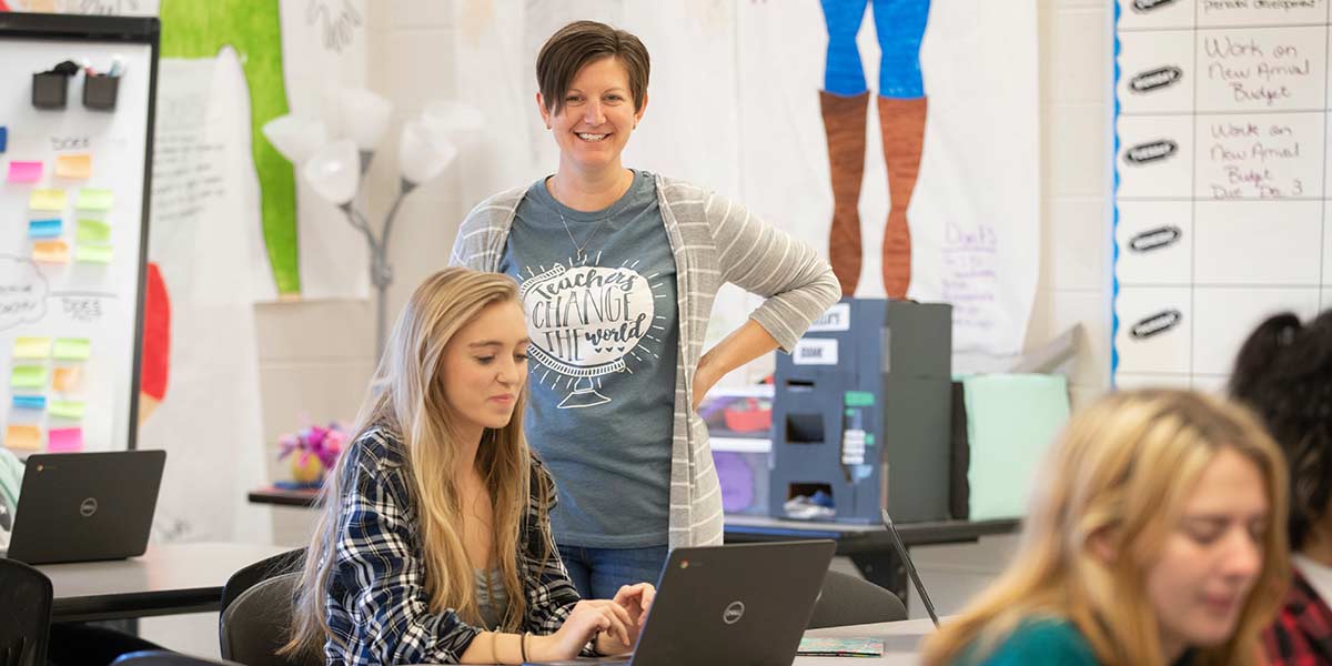 Jennifer Baxter smiling and standing in her classroom with her students