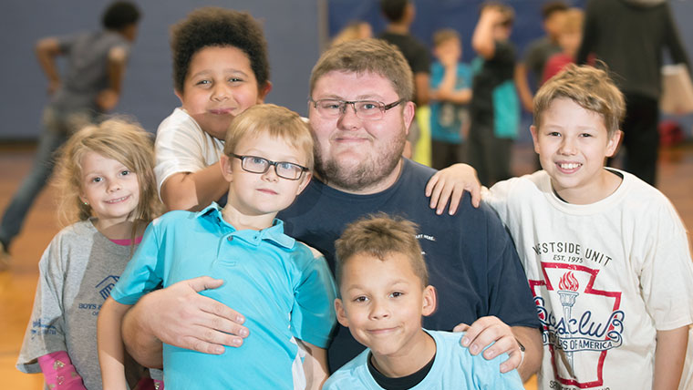 A teacher surrounded by students in a school gymnasium